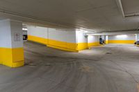 an empty parking space with yellow painted walls and concrete flooring and two cars parked