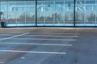 empty parking space with large windows next to a wall of glass doors that have been opened and are lit up