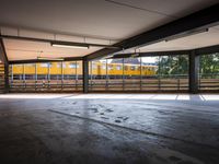 a empty parking space next to some windows in a building with a balcony area overlooking the train tracks