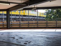 a empty parking space next to some windows in a building with a balcony area overlooking the train tracks
