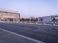 empty parking spaces along the road in front of buildings of many sizes and shapes with railings on either side