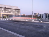 empty parking spaces along the road in front of buildings of many sizes and shapes with railings on either side