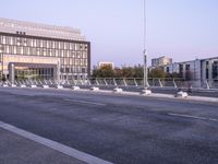 empty parking spaces along the road in front of buildings of many sizes and shapes with railings on either side