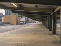 a long hallway with many empty parking spaces on either side of the street with buildings in the background