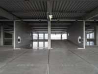 two empty parking spaces on concrete floors and ceilings with metal mesh dividers across them