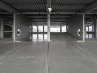 two empty parking spaces on concrete floors and ceilings with metal mesh dividers across them