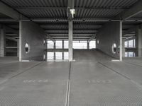 two empty parking spaces on concrete floors and ceilings with metal mesh dividers across them