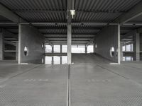 two empty parking spaces on concrete floors and ceilings with metal mesh dividers across them