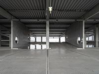 two empty parking spaces on concrete floors and ceilings with metal mesh dividers across them