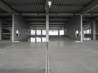 two empty parking spaces on concrete floors and ceilings with metal mesh dividers across them