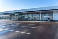 empty parking spaces for cars outside an open building with windows and an attached fence,