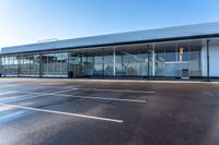 empty parking spaces for cars outside an open building with windows and an attached fence,