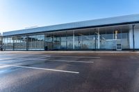 empty parking spaces for cars outside an open building with windows and an attached fence,