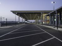 parking spaces in an empty airport with traffic at night time near terminal and entrance at dusk