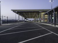 parking spaces in an empty airport with traffic at night time near terminal and entrance at dusk