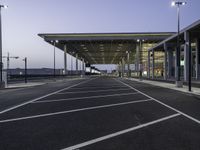 parking spaces in an empty airport with traffic at night time near terminal and entrance at dusk