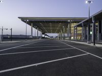 parking spaces in an empty airport with traffic at night time near terminal and entrance at dusk