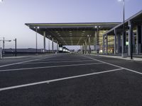 parking spaces in an empty airport with traffic at night time near terminal and entrance at dusk