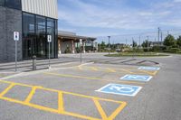 an empty parking lot with yellow and blue handicapped lanes on the road near the building