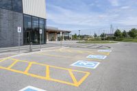 an empty parking lot with yellow and blue handicapped lanes on the road near the building