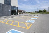 an empty parking lot with yellow and blue handicapped lanes on the road near the building