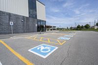 an empty parking lot with yellow and blue handicapped lanes on the road near the building