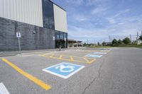 an empty parking lot with yellow and blue handicapped lanes on the road near the building