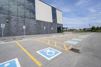 an empty parking lot with yellow and blue handicapped lanes on the road near the building