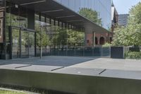 an empty patio of a city with trees in the background and large glass walls that divide the yard