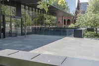 an empty patio of a city with trees in the background and large glass walls that divide the yard