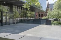 an empty patio of a city with trees in the background and large glass walls that divide the yard