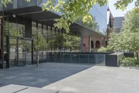 an empty patio of a city with trees in the background and large glass walls that divide the yard