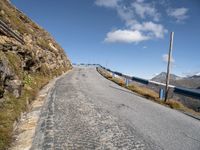 an empty paved mountain road with bridge on side of the roadway in a blue sky