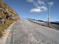 an empty paved mountain road with bridge on side of the roadway in a blue sky