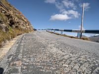 an empty paved mountain road with bridge on side of the roadway in a blue sky