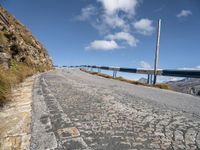 an empty paved mountain road with bridge on side of the roadway in a blue sky