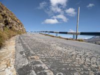 an empty paved mountain road with bridge on side of the roadway in a blue sky