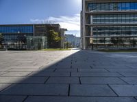 the empty paved walkway in front of the buildings and grass, with blue sky in background