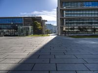 the empty paved walkway in front of the buildings and grass, with blue sky in background