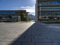 the empty paved walkway in front of the buildings and grass, with blue sky in background