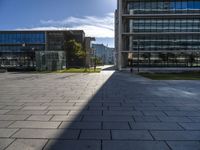 the empty paved walkway in front of the buildings and grass, with blue sky in background