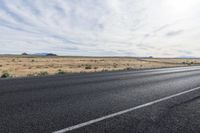 a motorcycle is parked near an empty stretch of asphalt in an empty plain with a bright sky