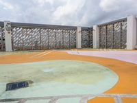 empty playground on a cloudy day with concrete walls and green, pink, yellow and orange colors