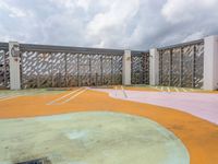 empty playground on a cloudy day with concrete walls and green, pink, yellow and orange colors