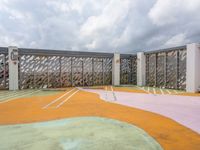 empty playground on a cloudy day with concrete walls and green, pink, yellow and orange colors