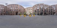 a 360 - view panoramic view shows an empty plaza in the city, with tall buildings and parking spaces