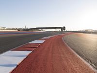 an empty track with red and blue stripes near a highway with a bridge in the background