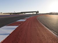 an empty track with red and blue stripes near a highway with a bridge in the background