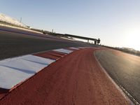 an empty track with red and blue stripes near a highway with a bridge in the background