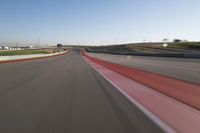 the race track is empty and red as the car drives past it on its way to a win